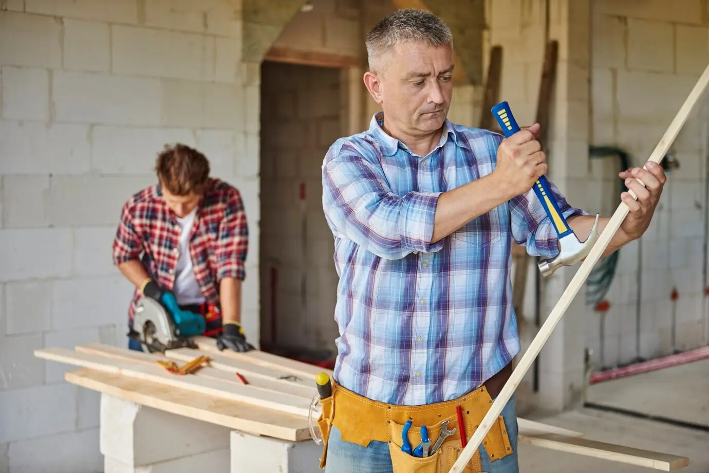 A motivated carpenter using a hammer is the primary subject.