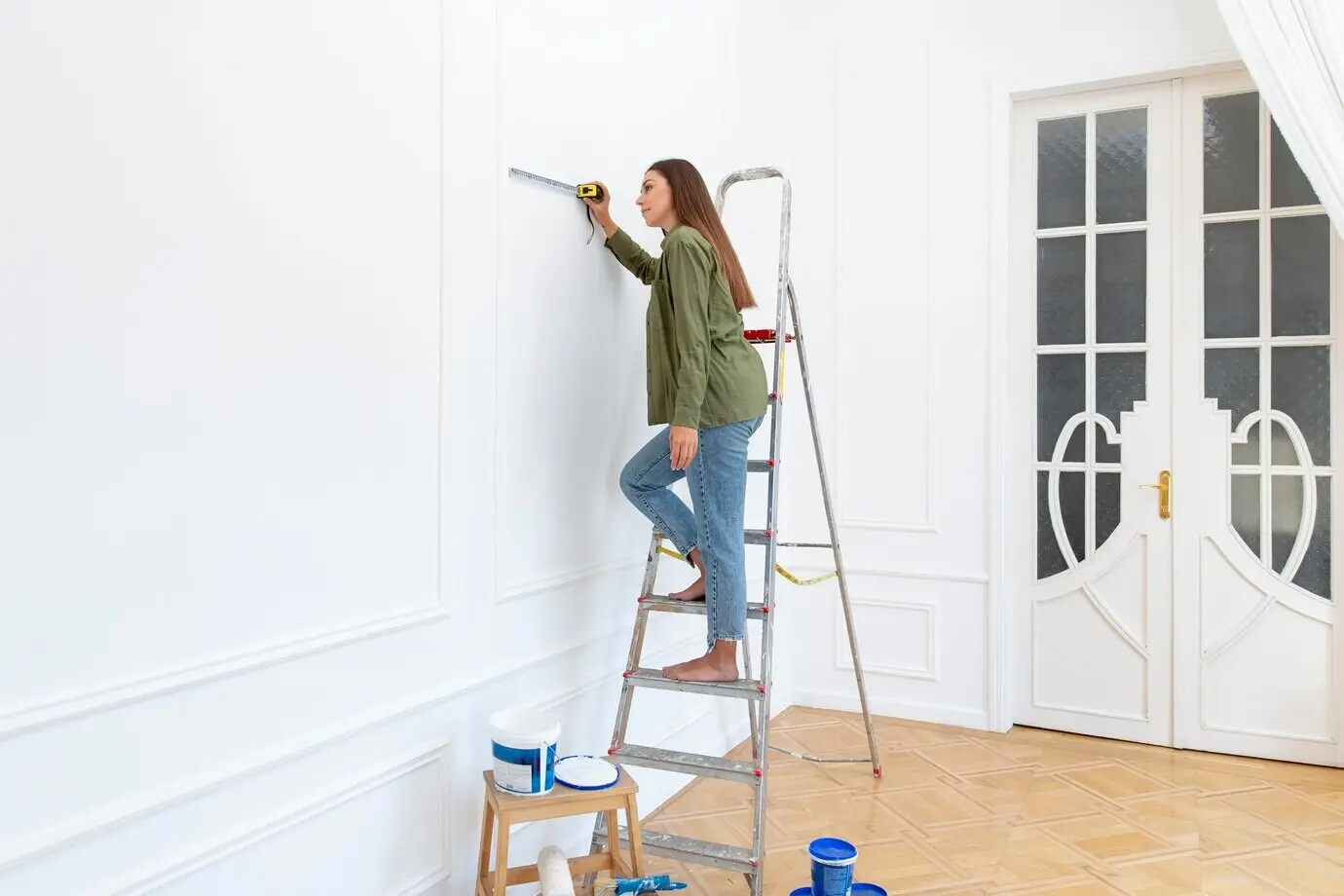 A full-body shot of a woman standing on a ladder.
