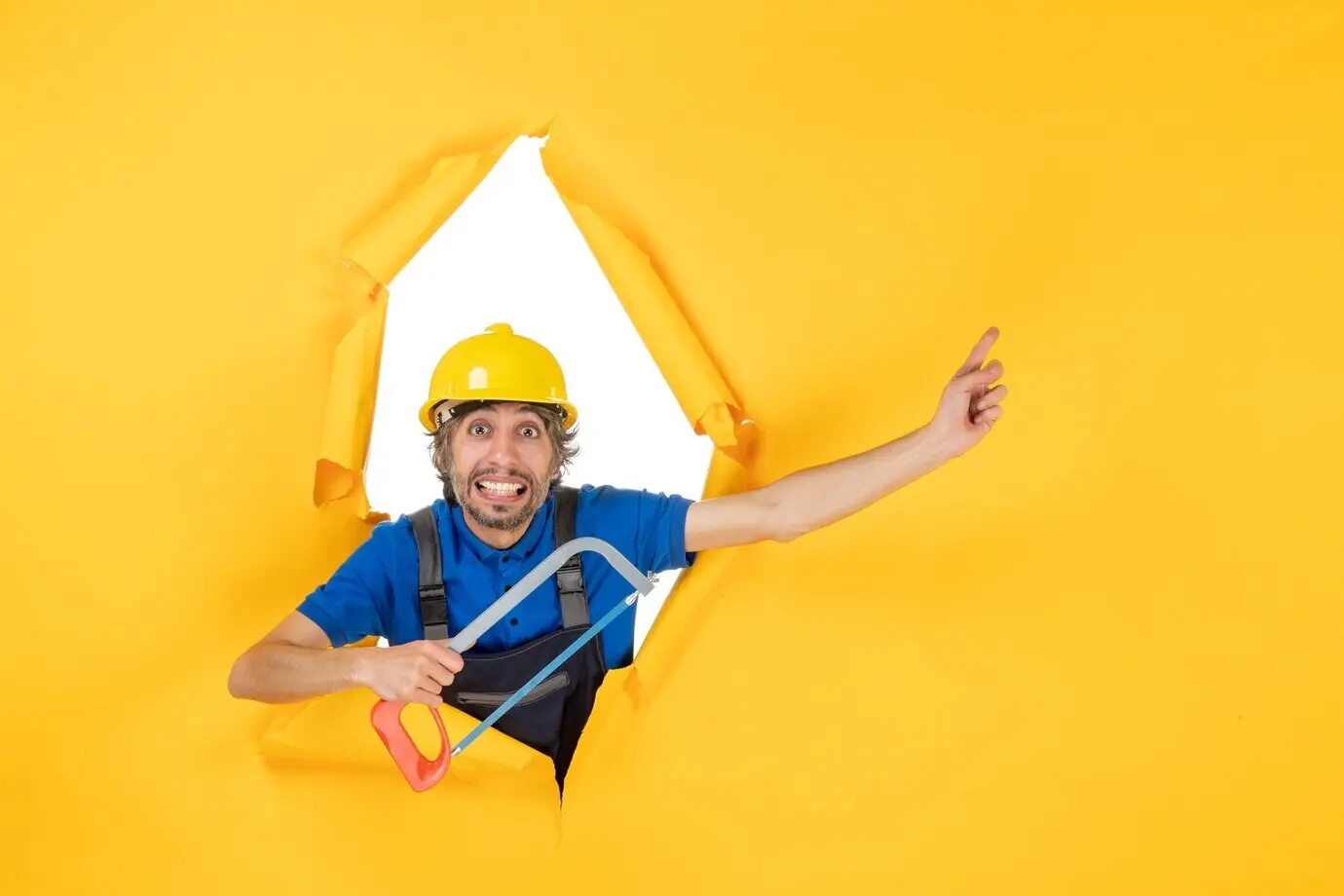 Front view of a male builder in uniform holding a bowsaw against a yellow background.